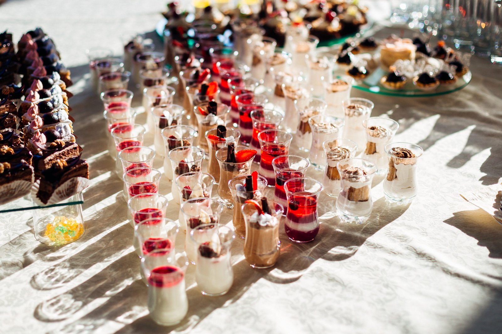 Tasty cold desserts with fruits and cheese stand on the white table illuminated by the sun